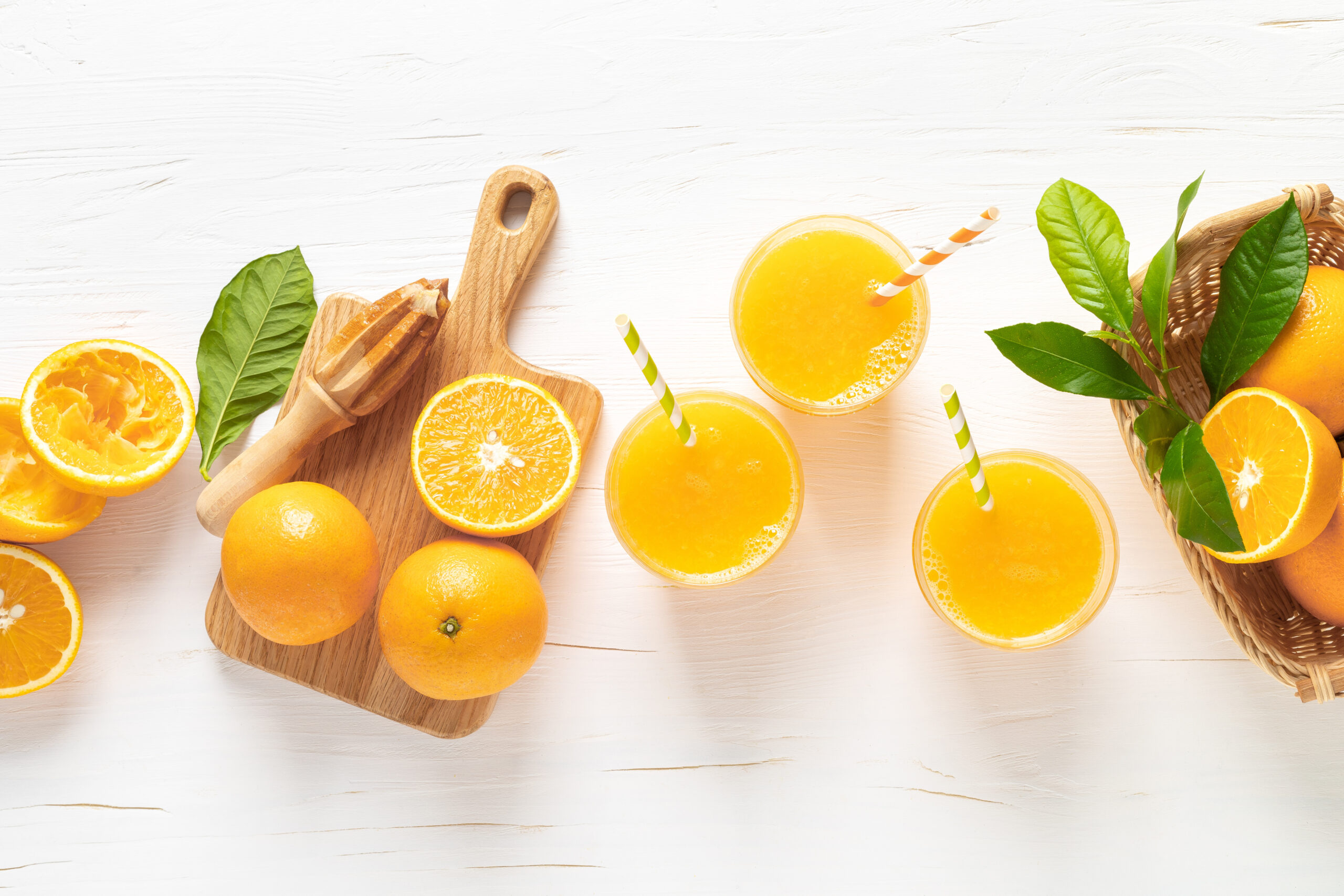 Jus d'orange. Jus fraîchement pressé dans des verres et fruits frais avec des feuilles, vue de dessus.